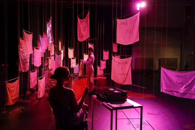 Kasia Wolinska sitting at typewriter with Britta rehanging banners, Tanzfabrik Berlin, June 2021 – photo by Anja Weber
