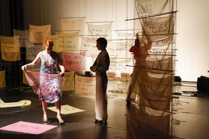 Britta talking about the recipe card "Documentation vs. Art Creation" with Kasia arranging banners and William rehanging banners, Tanzfabrik Berlin, June 2021 – photo by Anja Weber