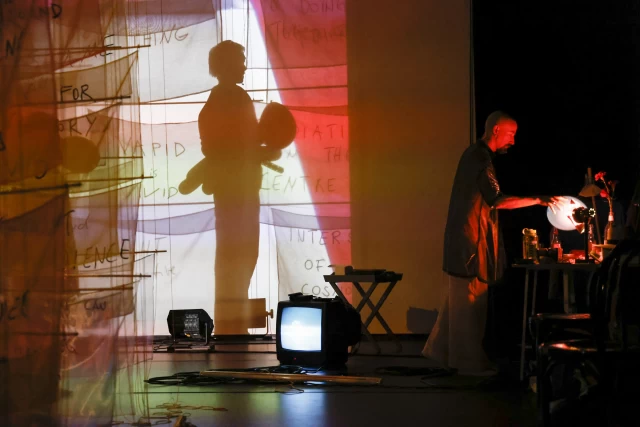 Britta's shadow in Justine and Margaret's video projection with original 1975 video of Try Leather playing on monitor and William in dressing area, Tanzfabrik Berlin, June 2021 – photo by Anja Weber